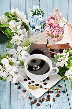 Spring apple blossoms and a cup of black coffee on blue wooden table