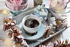 Spring apple blossoms and a cup of black coffee in a tray on blue wooden table