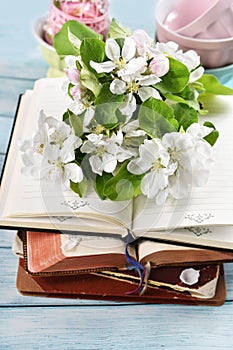 Spring apple blossoms and old books on blue wooden table