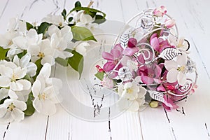 Spring apple tree blossoms and vintage cage heart on white old wooden background. Wedding or valentine concept.