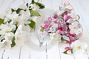 Spring apple tree blossoms and vintage cage heart on white old wooden background. Wedding or valentine concept.