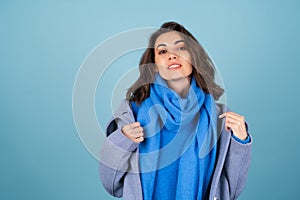 Spring autumn portrait of a woman in a blue knitted sweater, scarf and gray coat