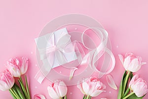 Spring background with bouquet of tulip flowers and gift box on pink table. Greeting card for 8 March International Women Day.