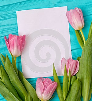 Spring background with bouquet of tulips and blank sheet of paper for romantic entries.