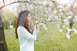 Spring background girl enjoying smell in a flowering garden . copy space . happy young woman