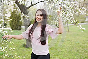 Spring background girl enjoying smell in a flowering garden . copy space . happy young woman