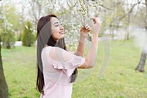 Spring background girl enjoying smell in a flowering garden . copy space . happy young woman