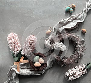 Spring background with quail feather wreath, pink hyacinth flowers, birds nest with Easter eggs and towel