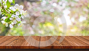 Spring background with white blossoms, sunlights in front of a wooden table and blurred background