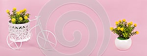 Spring banner, toy bike with potted flowers in basket on pink background, copy space for design. Flower delivery minimal concept.