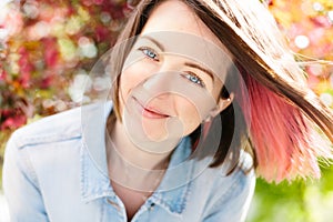 Close up portrait of a beautiful girl with pink hair standing in a blooming apple garden. Spring, outdoors.