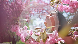 Spring Beauty Portrait of a Woman at Blossoming Sakura Tree on Nature