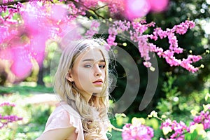 Spring bloom concept. Beautiful female face with perfect skin. Girl on dreamy face, tender blonde near violet flowers of