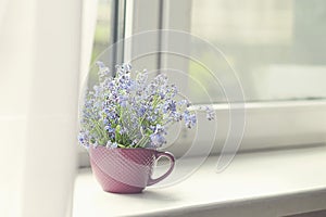 Spring bouquet of flowers and a cozy white plaid on the windowsill. white curtains cover part of the window