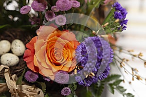 Spring bouquet of flowers with orange rose and purple flower in the background