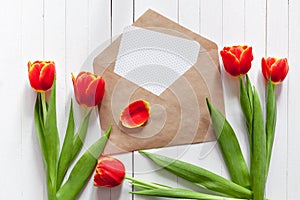 Spring bouquet of red tulips and a card in an envelope