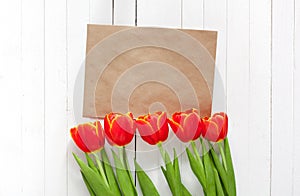 Spring bouquet of red tulips and a card in an envelope