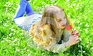 Spring break concept. Child enjoy spring sunny day while lying at meadow with daisy flowers. Girl lying on grass