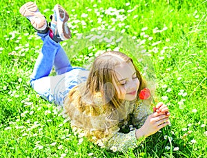 Spring break concept. Child enjoy spring sunny day while lying at meadow with daisy flowers. Girl on smiling face holds