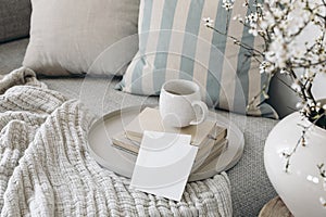 Spring breakfast scene. Blank greeting card mockup. Cup of coffee, tea on books. Round beige tray. Blossoming cherry