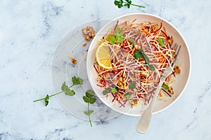 Spring carrots, beets, cabbage salad with nuts and herbs in white bowl