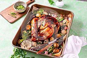 Spring chicken baked with radishes and green peas in one-pot on a green background.