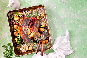 Spring chicken baked with radishes and green peas in one-pot on a green background.