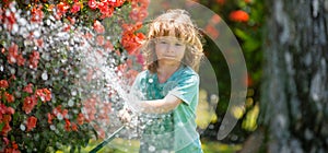 Spring child watering, banner. Child watering flowers and plants in garden. Kid with water hose in backyard. Kids