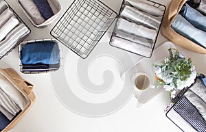 Spring cleaning of closet. Vertical tidying up storage. Neatly folded clothes in the metal black baskets for wardrobe. White