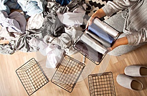 Spring cleaning of closet. Vertical tidying up storage. Neatly folded clothes in the metal black baskets for wardrobe. Wooden