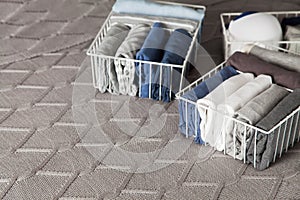 Spring cleaning of closet. Vertical tidying up storage. Neatly folded clothes in the metal white baskets for wardrobe. Grey