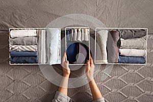 Spring cleaning of closet. Vertical tidying up storage. Neatly folded clothes in the metal white baskets for wardrobe. Grey