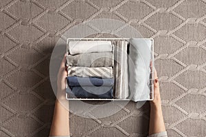 Spring cleaning of closet. Vertical tidying up storage. Neatly folded clothes in the metal white baskets for wardrobe. Grey