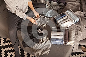 Spring cleaning of closet. Vertical tidying up storage. Neatly folded clothes in the metal white baskets for wardrobe. Nordic