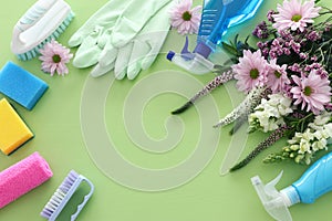 Spring cleaning concept with supplies over pastel green wooden background. Top view, flat lay