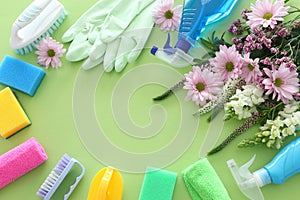 Spring cleaning concept with supplies over pastel green wooden background. Top view, flat lay