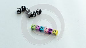 Spring coming and changing winter. Spring concept. Colorful letter beads on white background.