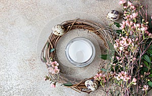 Spring composition with braided wreath of twigs with flowers, quail eggs and candle. Easter wreath or nest from rattan. DIY