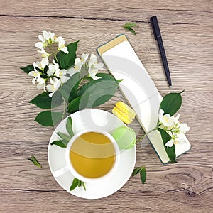 Spring composition of cup of tea, notebook and flowers on wooden table, flat lay