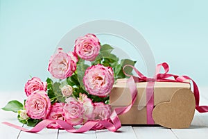 Spring composition with pink flowers rose and gift box on vintage table. Greeting card for Birthday, Woman or Mothers Day.