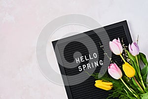 Spring concept. Pink and yellow tulips and letterboard with quote Hello Spring