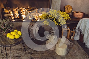 Spring cosy decorations in house interior with fireplace and mimosa. Cosy home concept