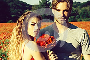 Spring couple with flower bouquet in field of poppy, couple in love. Horny hot young people embracing.