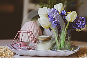 Primavera decoraciones sobre el sobre el mesa en escandinavo estilo flores a aromático velas 