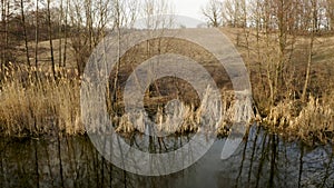 Spring duck hunting, a hunter hidden in a hut on the river shoots a rifle at wild drakes, aerial video