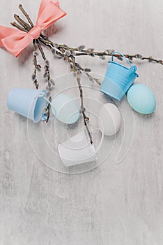 Spring easter blue eggs and willow branches tied with a pink ribbon and with small buckets on a grey wooden table. Top view, space