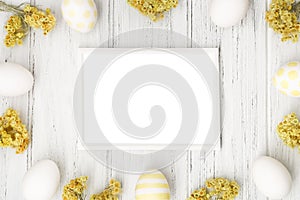 Spring Easter frame with eggs, yellow flowers and copy space, flat lay. Easter mockup, template on the white wooden background