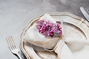 Spring elegant table place setting with violet lilac, silverware on vintage table. Close up. photo