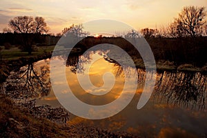 spring evening sunset over the river with a mirror reflection of clouds in the water