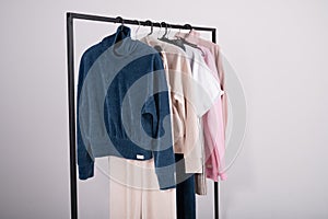 Spring fashion casual clothes hanging on a rack. Stylish female t-shirts  hoodie  pants on hanger on white background. Fashion